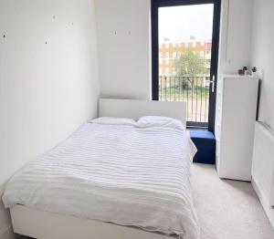 Cama blanca en habitación blanca con ventana en Beautiful 2 Bed Apartment In Bow en Londres