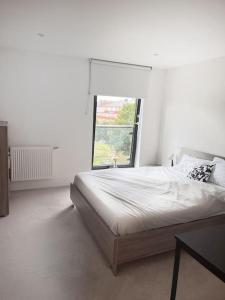 Habitación blanca con cama y ventana en Beautiful 2 Bed Apartment In Bow en Londres
