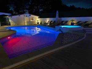 a swimming pool at night with blue lights at Villa Sany:10 Pers Maison 200m2 piscine , jacuzzi in Narrosse