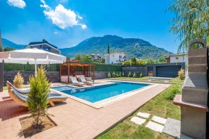 a backyard with a swimming pool and an umbrella at Luxurylifevillas 5-6 in Fethiye