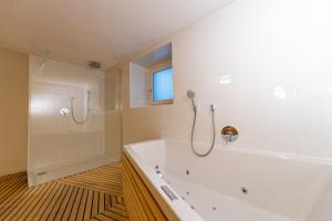 bagno bianco con vasca e doccia di Villa Vastle a Ortisei