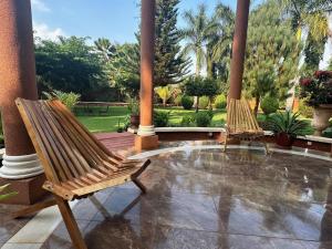 two wooden chairs sitting on a patio with palm trees at Kilimanjaro Pazuri Villas in Moshi