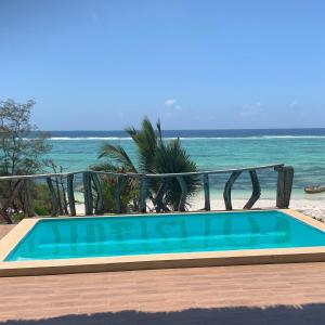 a swimming pool with the ocean in the background at Zi Villa Beach Cottage in Matemwe