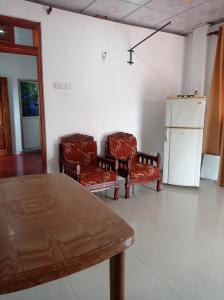 a room with two chairs and a table and a refrigerator at Weligama Elite Guest in Weligama