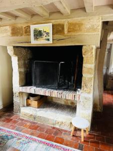 un camino in pietra con TV in camera di L’Agapé : Le charme absolu de la Normandie a Saint-Pierre-Azif