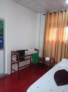 a room with two beds and a chair and a window at Weligama Elite Guest in Weligama