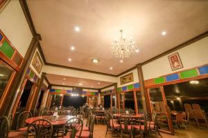 a dining room with tables and chairs and a chandelier at ดอยหมอกดอกไม้รีสอร์ท DoiMok DokMai Resort in Mae Salong