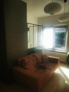 ein Sofa im Wohnzimmer mit Fenster in der Unterkunft Studio - un lit en ville in Ath