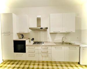 a white kitchen with white cabinets and a sink at Dolce Casa in Casalabate