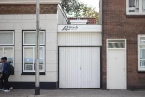 twee witte garagedeuren op een bakstenen gebouw bij Hotel Steeds aan Zee in Katwijk