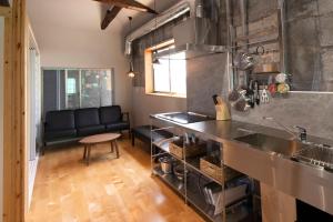 uma cozinha com um lavatório e um sofá num quarto em Etcetera Guest House em Niijimamura