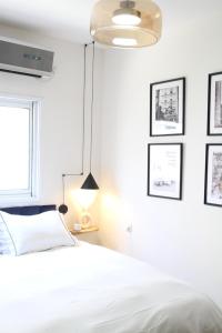 ein Schlafzimmer mit einem weißen Bett und gerahmten Bildern an der Wand in der Unterkunft Charming Old North near Park by FeelHome in Tel Aviv