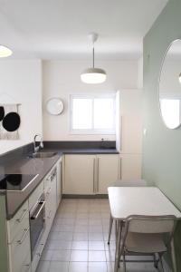a kitchen with white cabinets and a table and a window at Charming Old North near Park by FeelHome in Tel Aviv