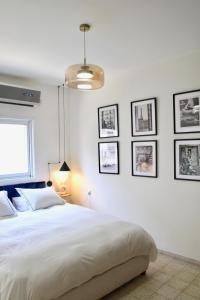 a bedroom with a bed and framed pictures on the wall at Charming Old North near Park by FeelHome in Tel Aviv