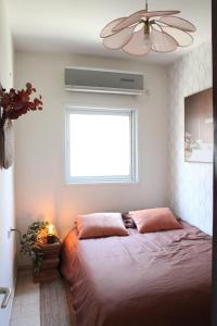 um quarto com uma cama, uma janela e uma ventoinha de tecto em Charming Old North near Park by FeelHome em Tel Aviv