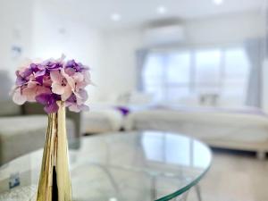 un jarrón con flores púrpuras sentado en una mesa de cristal en guesthouse Nakatsu en Osaka