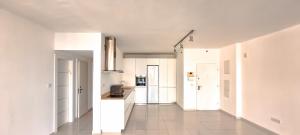 duża biała kuchnia z białymi szafkami i urządzeniami w obiekcie Spacious Condo in New North by FeelHome w Tel Awiwie