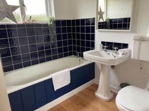 a bathroom with a tub and a sink and a toilet at The Gate-Lodge at Levally House in Monea