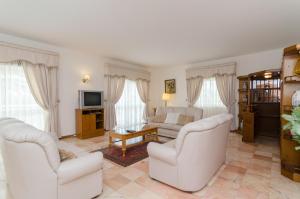 ein Wohnzimmer mit zwei weißen Stühlen und einem Sofa in der Unterkunft Villa Do Monte in Monte Raposo