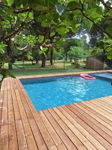 a pool with a wooden deck and a red frisbee at La Pinède du Chéou, Piscine, Logement indépendant, Parking, Draps, Wifi fibre in Mimizan