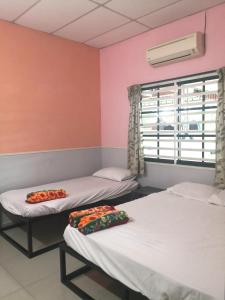 two beds in a room with a window at Hua Tang Homestay in Ipoh