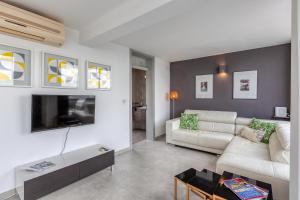 a living room with a white couch and a tv at 49/3 Seafront Duplex Penthouse in Valletta in Valletta