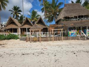 a resort on the beach with palm trees in the background at Kibwana Village Bungalows in Matemwe