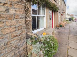 a stone building with a window and some plants at Wether Fell View in Hawes