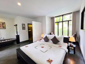 暹粒的住宿－The Bliss Angkor，一间卧室配有一张白色大床,床上有鲜花