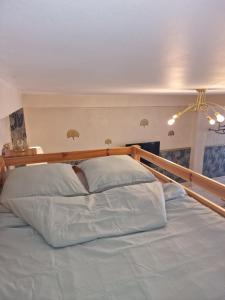 1 cama grande con sábanas blancas y cabecero de madera en L'émeraude : studio chic et élégant, en Agde