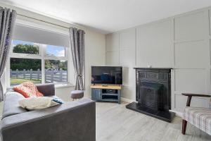 a living room with a couch and a tv and a fireplace at The Wee House in Muff