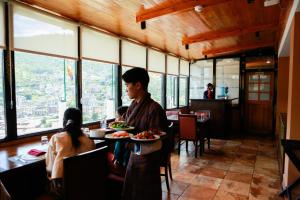 Ein Mann sitzt an einem Tisch mit einem Teller Essen in einem Restaurant. in der Unterkunft Phuntsho Khangsar Hotel in Thimphu