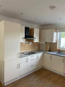 a white kitchen with white cabinets and a window at Whole Apartment Near to London in Bromley