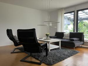 a living room with a black chair and a table at Mergl's in Bad Schonborn