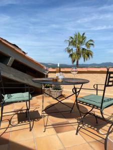 un patio con una mesa, sillas y una palmera en Les Trois soleils, en Roquebrune-sur-Argens