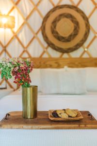 een houten snijplank met koekjes en een vaas met bloemen bij Camposanto Glamping - The Macaw Yurt in Austin
