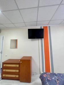 Habitación con TV en la pared y tocador en Uneed Rooms Sakvoiaj, en Kiev