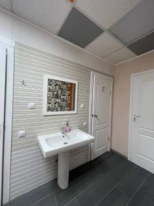 łazienka z białą umywalką i drzwiami w obiekcie Uneed Rooms Sakvoiaj w Kijowie