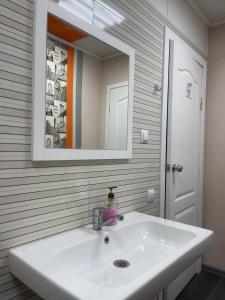 W łazience znajduje się biała umywalka i lustro. w obiekcie Uneed Rooms Sakvoiaj w Kijowie