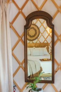 a mirror on a wall with a bed in a room at Camposanto Glamping - The Macaw Yurt in Austin