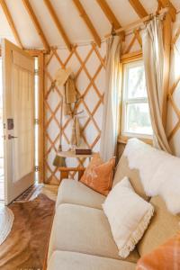 sala de estar con sofá y ventana en Camposanto Glamping - The Macaw Yurt en Austin