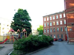 a playground in a city with a tree and buildings at Apartments Statskij Sovetnik in Saint Petersburg