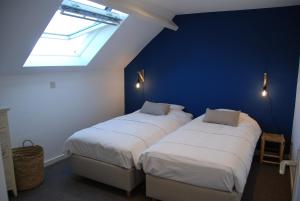 two beds in a room with a blue wall at The Little House in Beersel