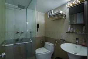 La salle de bains est pourvue de toilettes, d'un lavabo et d'une douche. dans l'établissement Shinepukur Suites at Concord, à Dhaka