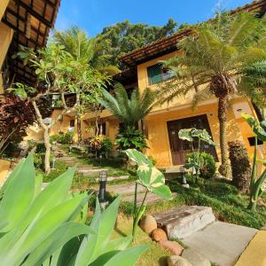 une maison avec des palmiers devant elle dans l'établissement Villa Garoupeta - Apartamentos, à Bombinhas