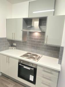 a kitchen with white cabinets and a stove top oven at SEV Apartments Wakefield in Hemsworth
