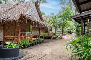 uma casa com telhado de palha e plantas na frente em Breeze Bungalows em Ko Lanta