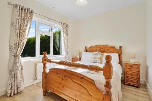 een slaapkamer met een houten bed en een raam bij Ardmore Cottage - Failte Ireland Quality Assured in Muff