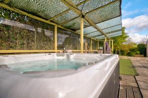 a jacuzzi tub in a backyard with a pergola at Howgills Barn in Sedbergh