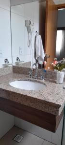 a bathroom counter with a sink and a mirror at Casa Jardins da Lagoa in Caldas Novas